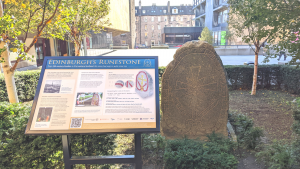 Photo of a carved runestone slab with an interpretation board