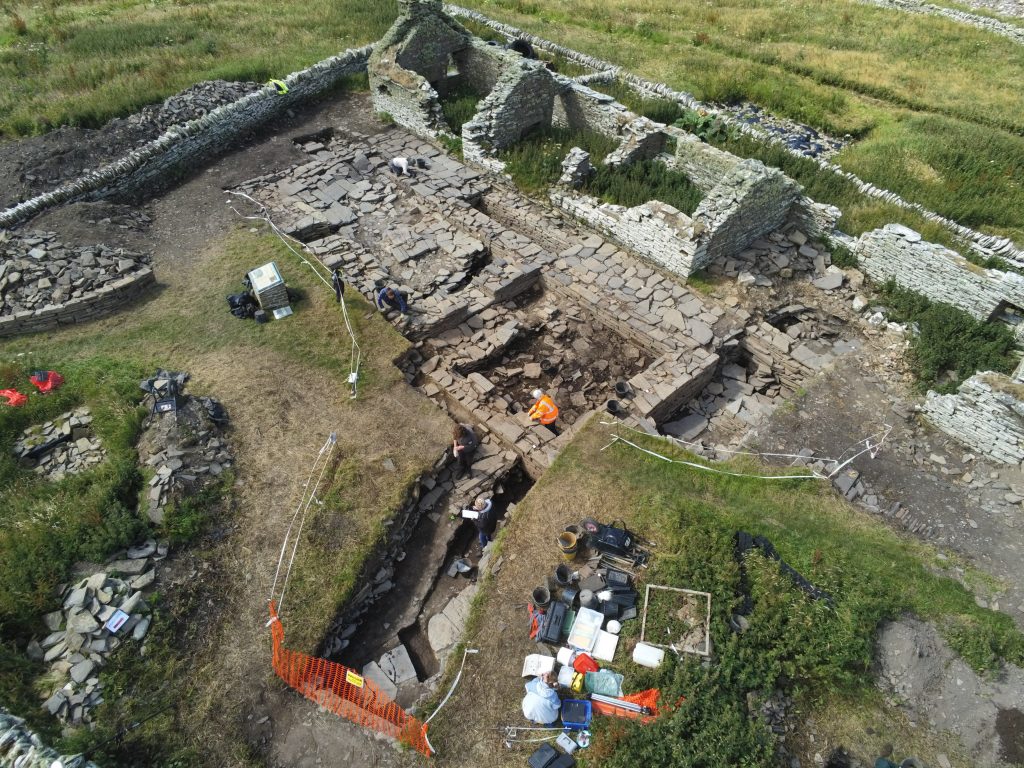 Aerial photo of an excavated farm site with the remains of stones walls visible