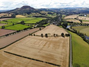 Aerial photo of fields in rural Scotland with a hill in the background