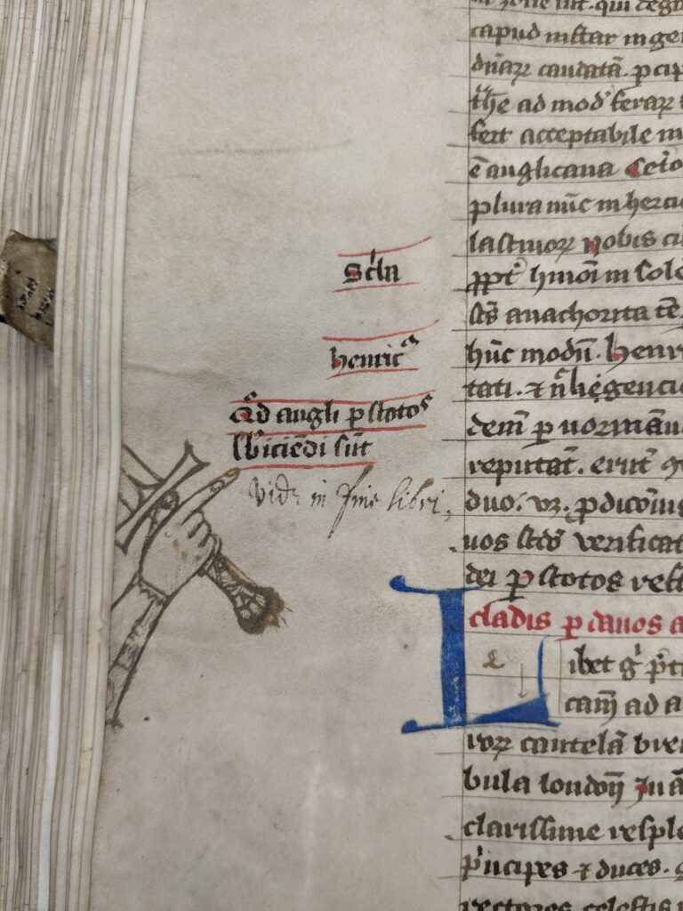 Photo of a manuscript page showing a drawing of a raised and pointed hand in the margin holding a sword and positing to some annotations