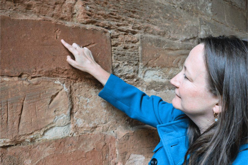 Person pointing at a mark in a stone wall