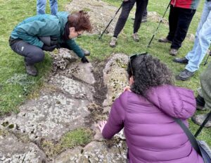 People looking at patterns carved into a rocky outcrop in the ground