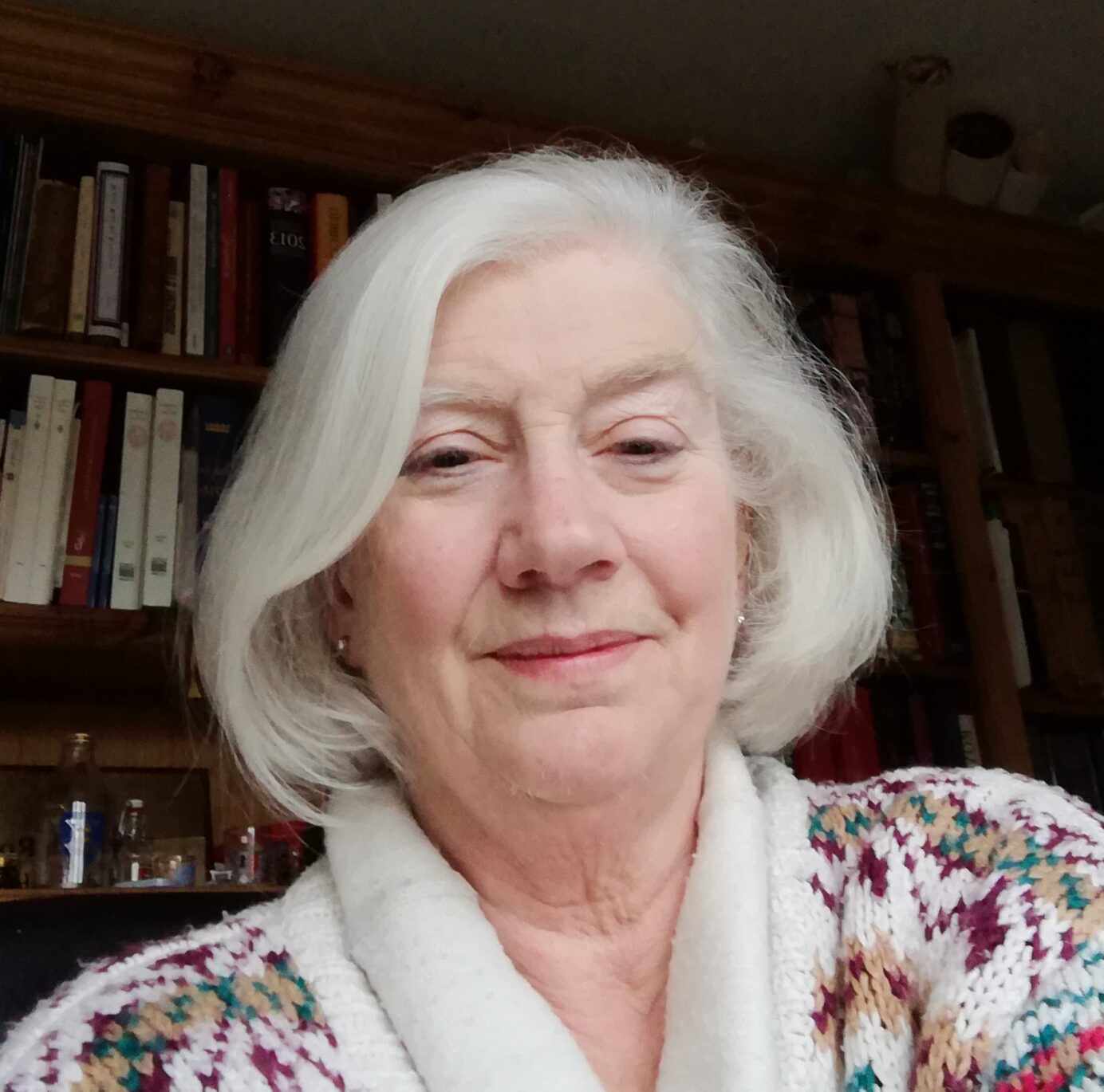 Photo of a woman with white chin-length hair wearing a patterned sweater