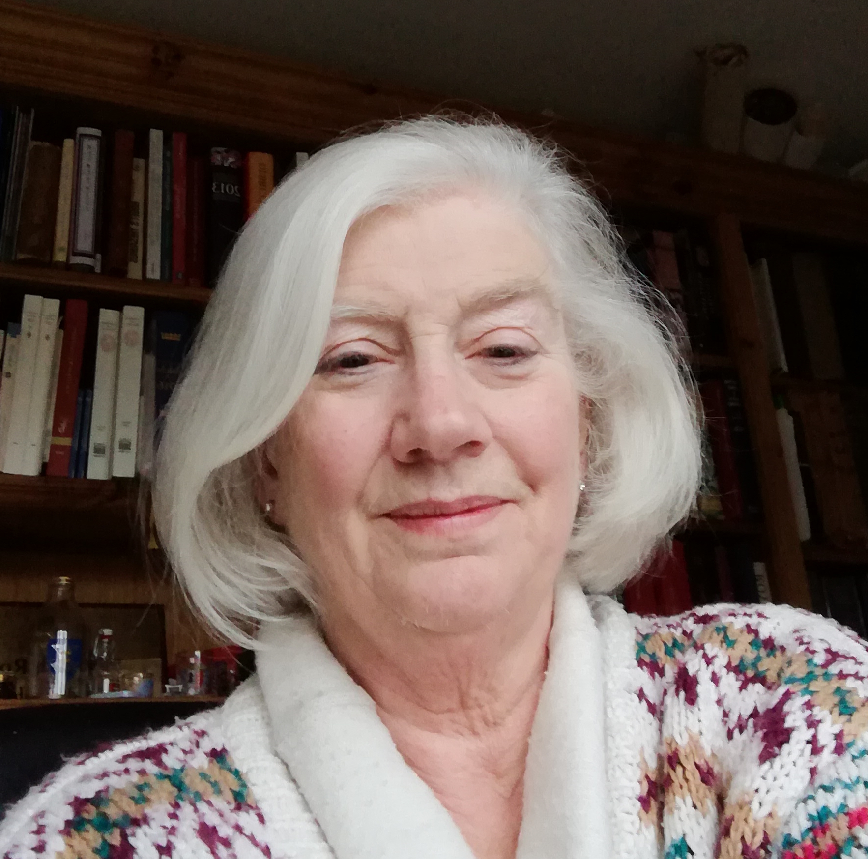 Photo of a woman with white chin-length hair wearing a patterned sweater