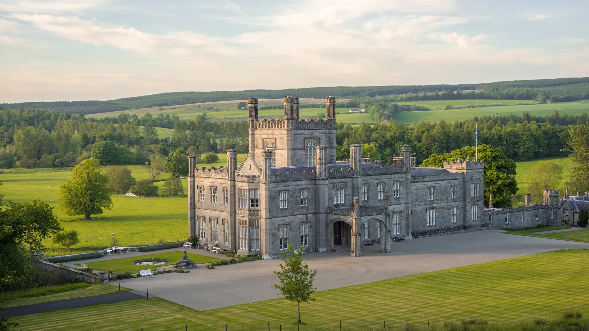 blairquhan-castle-front-view-hero-1920x1080-1 The impressive front elevation of Blairquhan Castle, showcasing its distinctive baronial architecture, towers, and grand entrance.