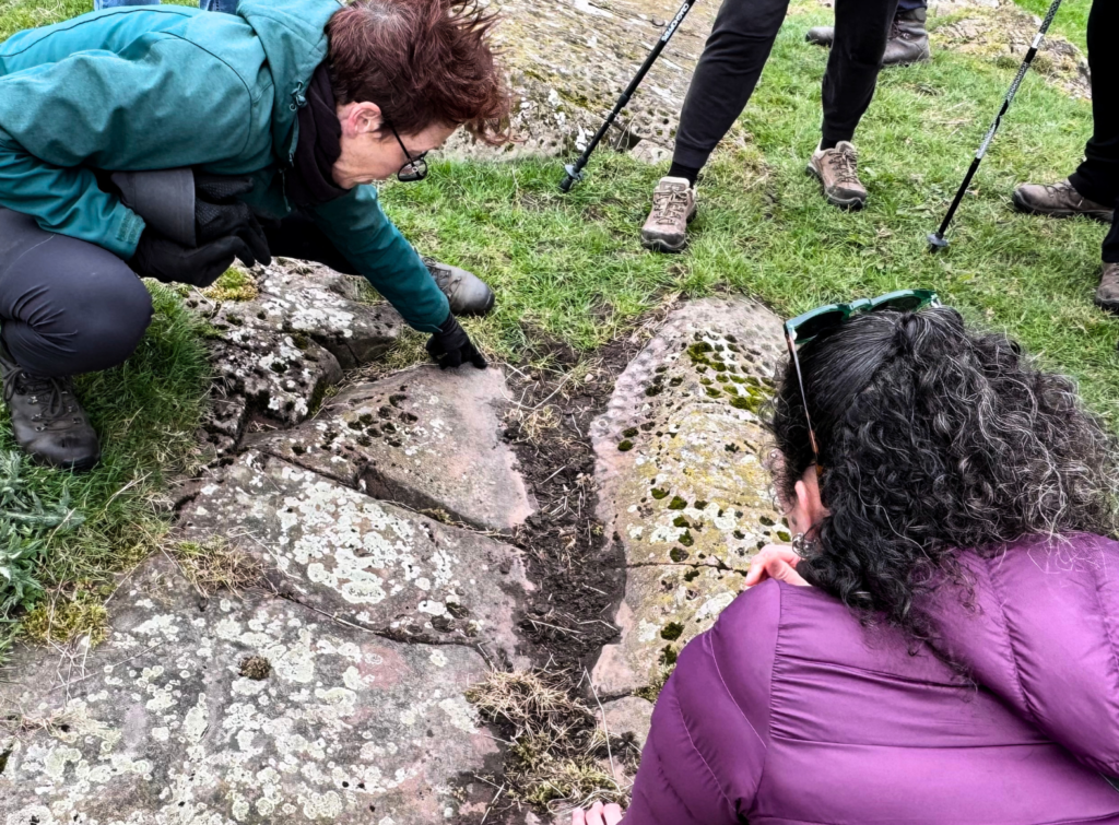 Two people kneeling down near a rock with decorations in it