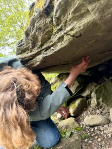 Someone in outdoor clothing leaning by and looking at a rocky outcrop